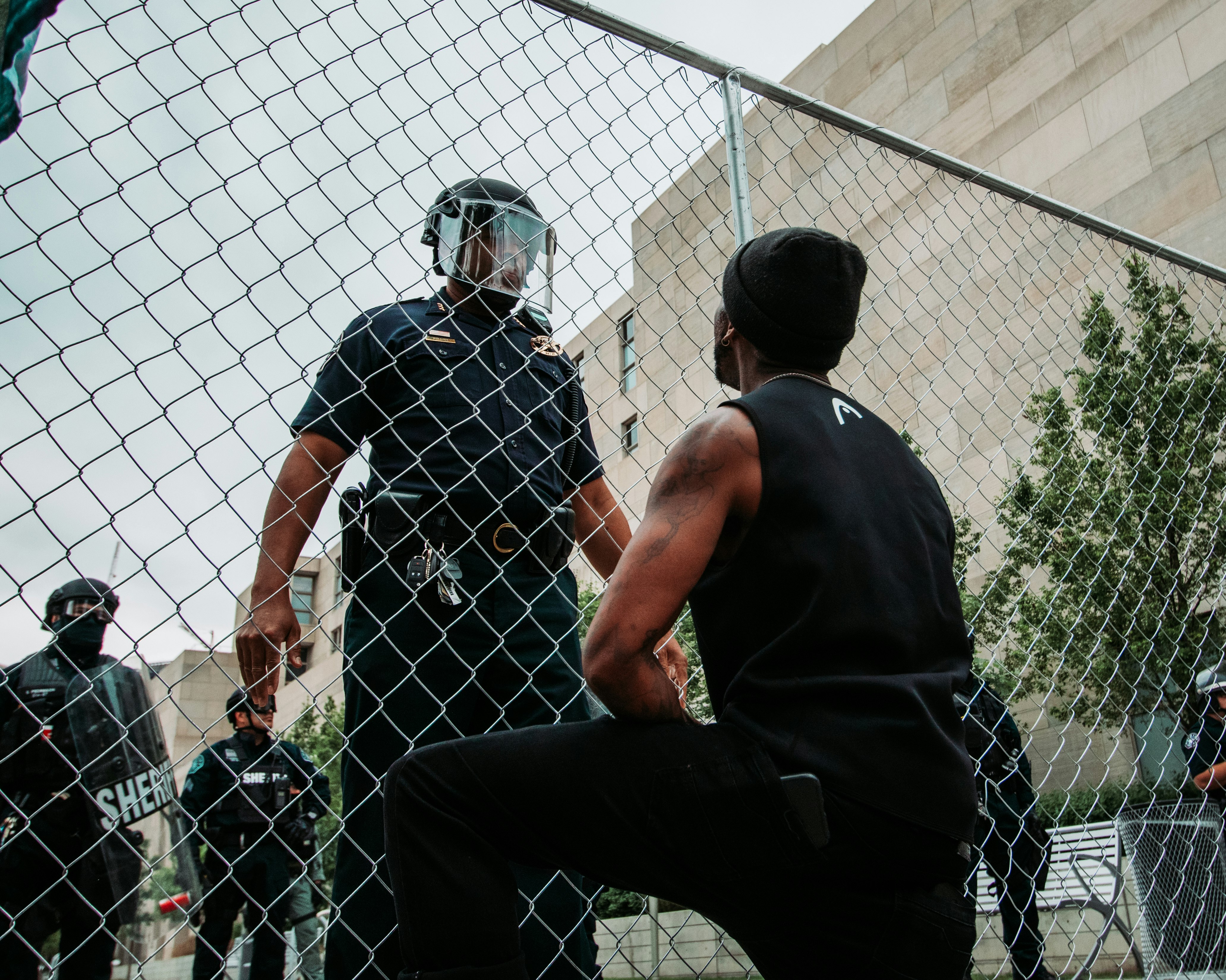 man in black t-shirt and black pants standing beside fence during daytime